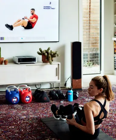 A woman doing an F45 at-home workout in front of a TV