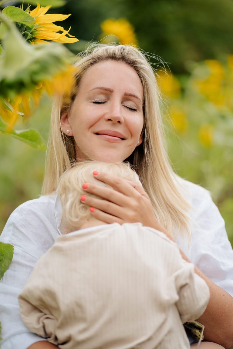 Mutter kuschelt ihr Kind unter Sonnenblumen