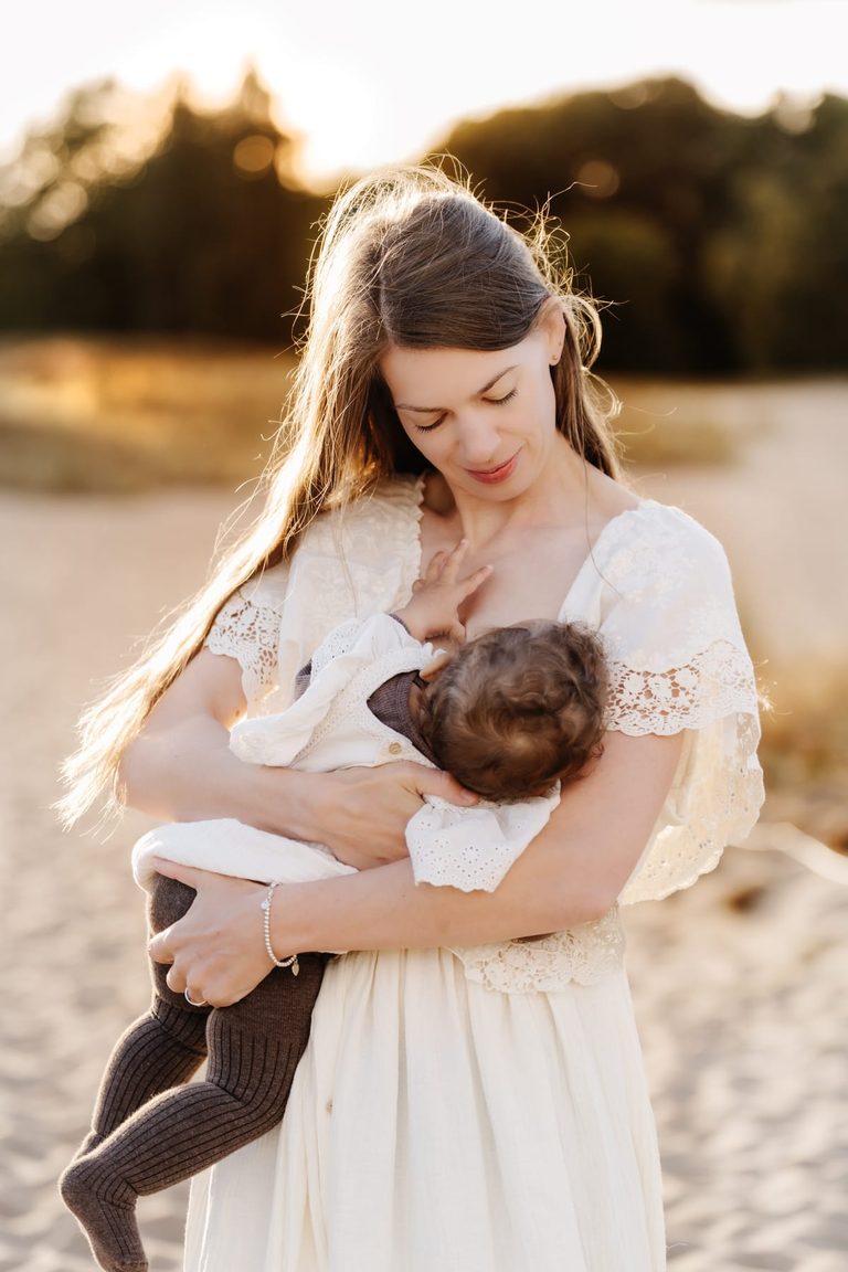 Mutter trägt ihr Baby über einen sonnigen Weg
