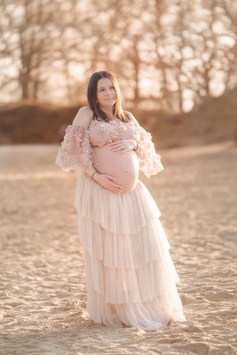 Schwangere im Tüllkleid am Wasser im Sonnenuntergang
