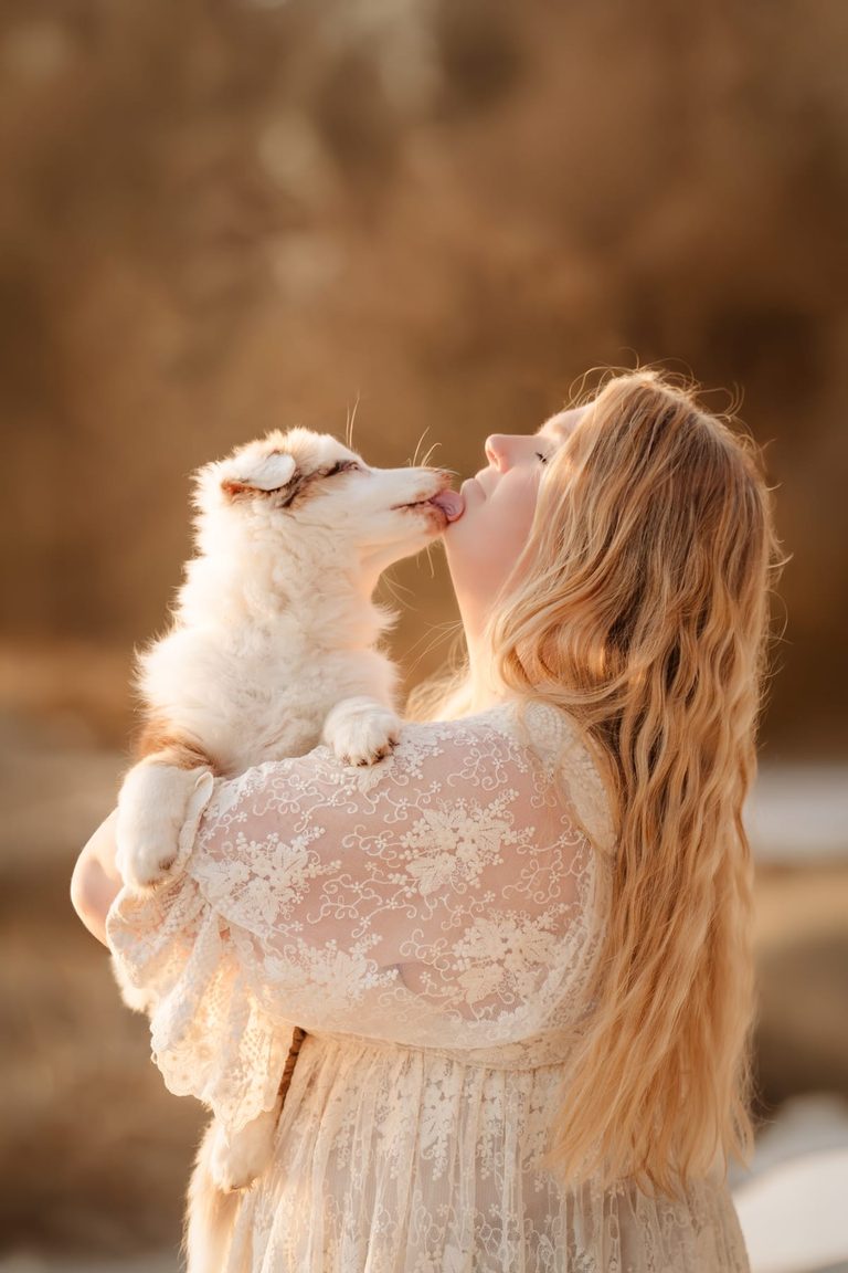 Coralie küsst einen jungen Hund im goldenen Abendlicht