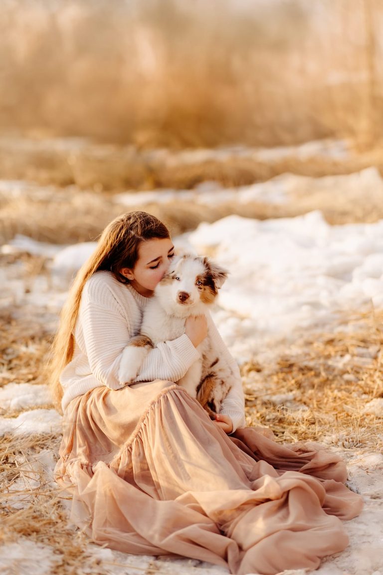 Frau umarmt ihren Hund im weichen Winterlicht