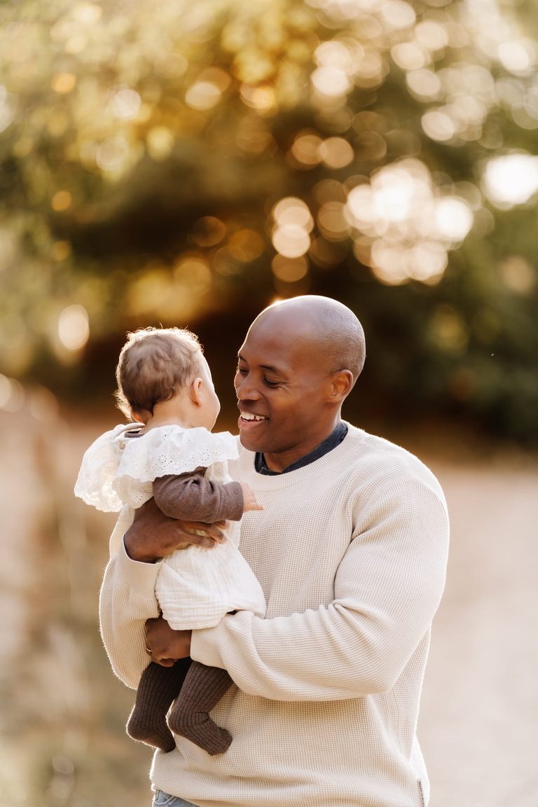 Vater spielt mit seinem Baby unter einem Baum