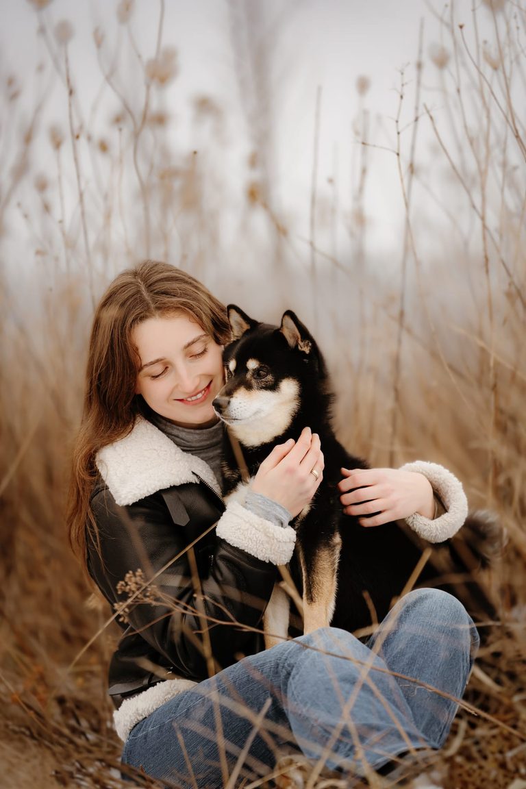 Junge Frau hält ihren kleinen Hund im Schilf