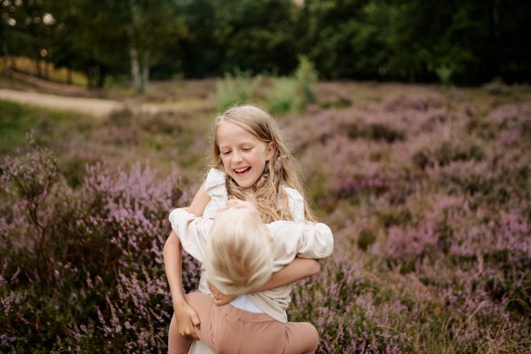 Mutter wirbelt ihr Kind durch die blühende Heide