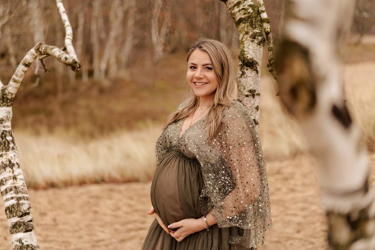 Schwangere im olivgrünen Kleid zwischen Birken