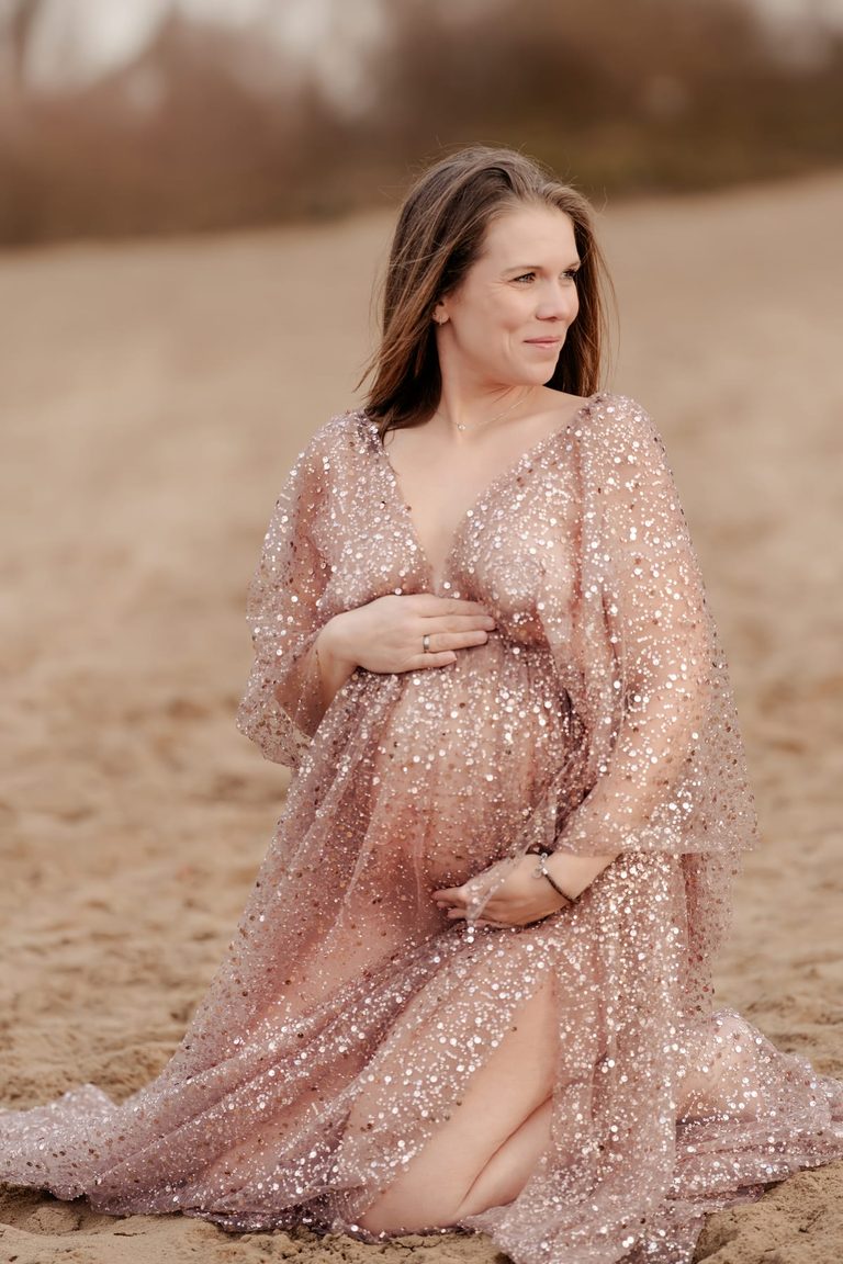 Schwangere im rosa Glitzerkleid in den Dünen