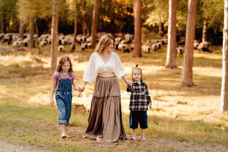 Mutter mit Kindern im Wald, Schafherde im Hintergrund