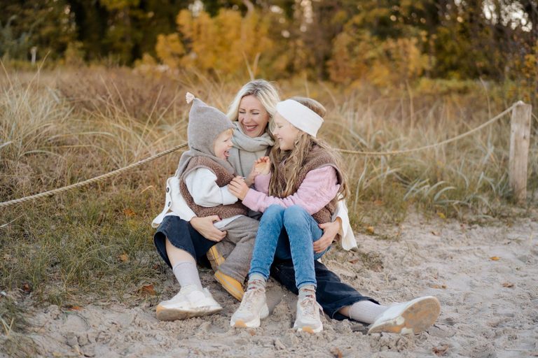 Familie sitzt lachend am Strand