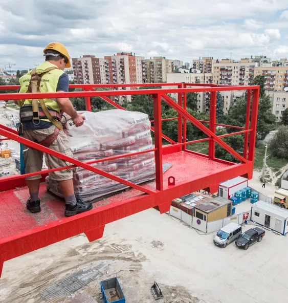 Monter na czerwonej platformie roboczej na placu budowy