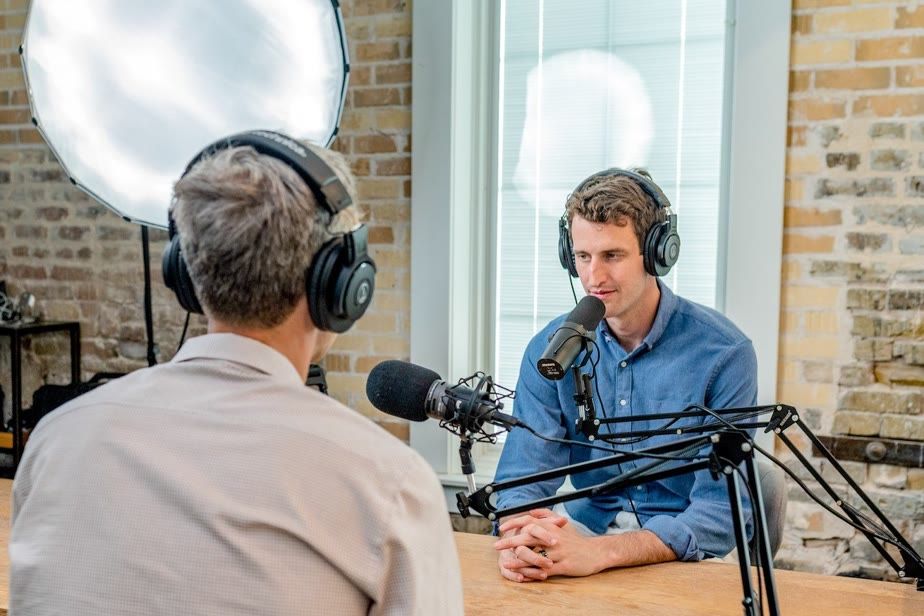 Two people with headphones talking at studio microphones