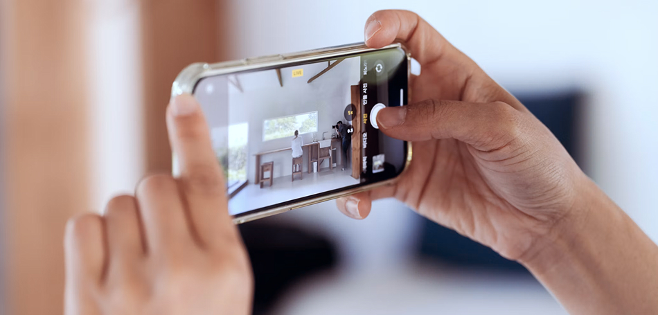 A person's hands holding a smartphone, with the screen showing a live view of a room interior.