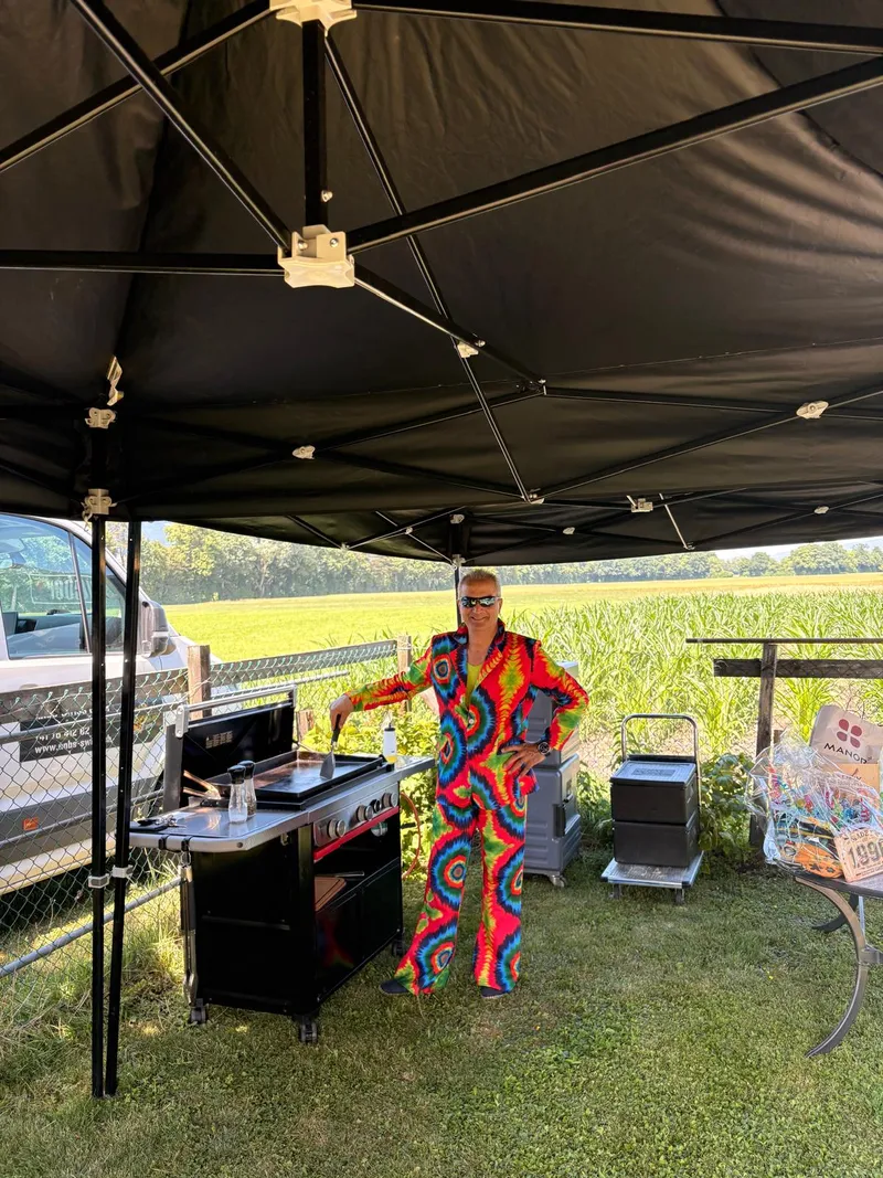 Grillkoch im bunten Partyanzug an einer mobilen Grillstation