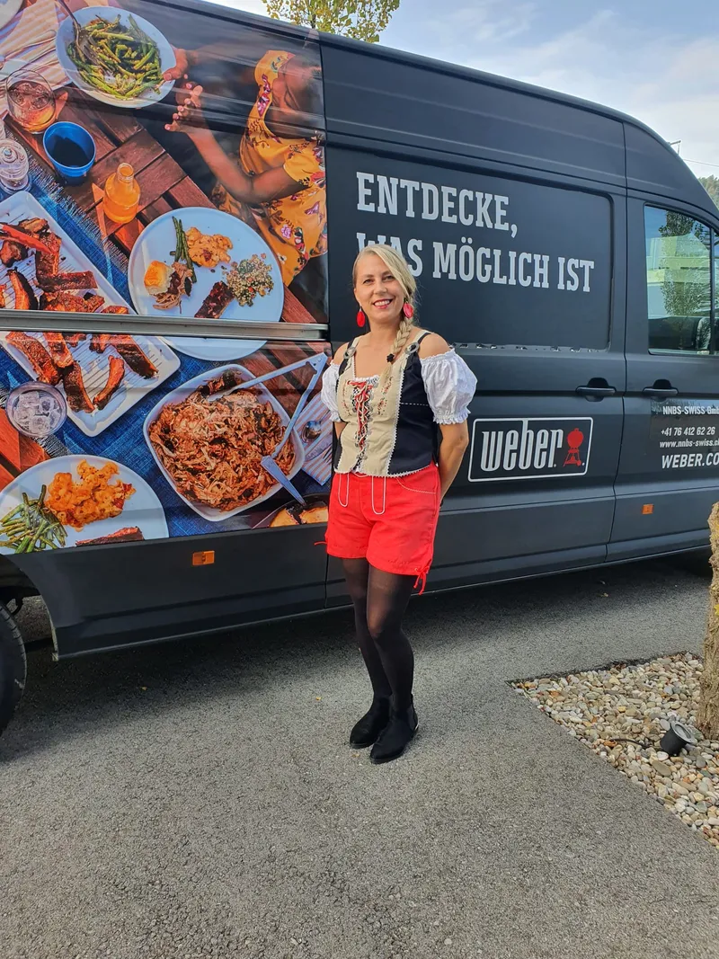 NNBS-Mitarbeiterin vor dem Weber-Foodtruck mit Grillgerichten