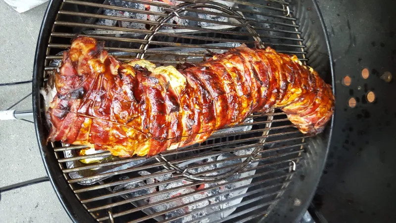 Glasierter Schweinebraten auf dem Rost eines Kugelgrills
