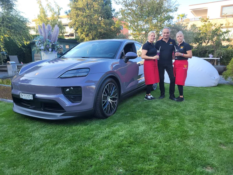 NNBS-Team serviert Drinks neben einem Porsche in einem Garten