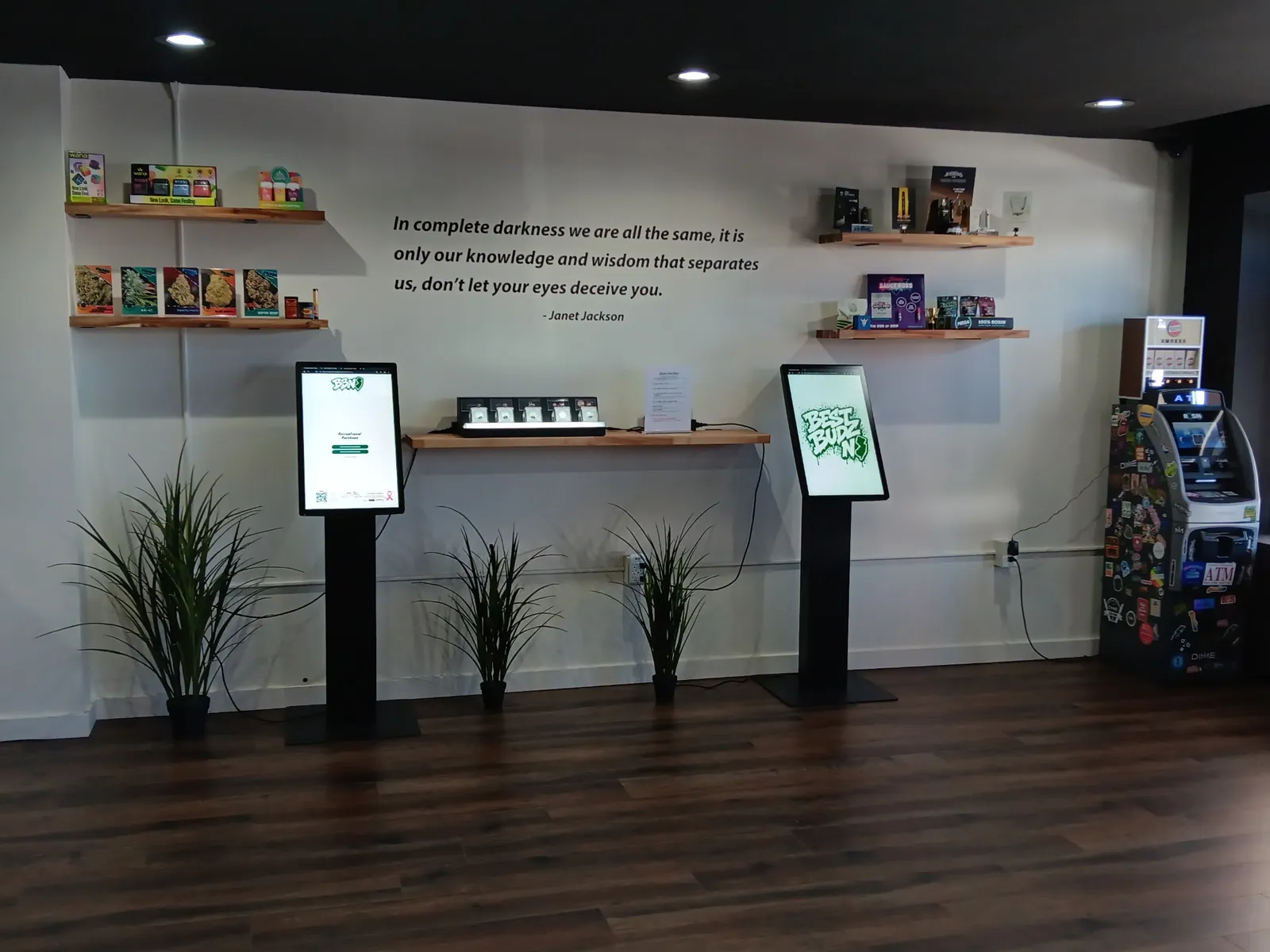 Two self-order kiosks under the Best Budz NJ wall quote, next to the product shelves