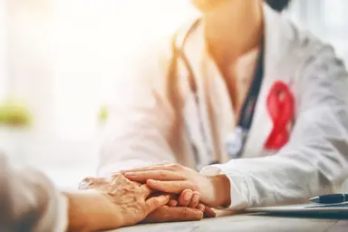 Laboratory professional and patient with hands resting together during a healthcare consultation.
