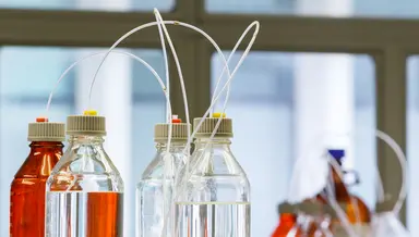Laboratory reagent bottles connected with tubing, representing quality control processes, system monitoring and troubleshooting activities in a diagnostic laboratory.