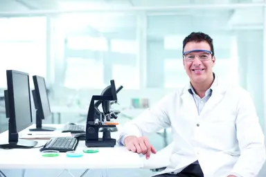 Scientist working in a laboratory with microscopy and analytical equipment to support diagnostic testing, research and assay development applications.