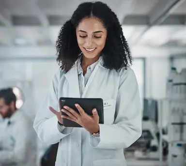 Laboratory professional reviewing testing data on a tablet in a clinical laboratory setting, representing quality control, analytical performance monitoring, calibration verification and quality management workflows.