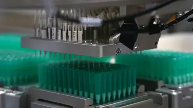 Automated liquid handling system processing labelled sample tubes and microplates for genomic analysis, representing NGS assay development, validation and clinical genomics reference materials used to support accurate variant detection.