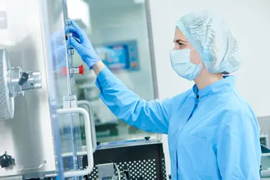 Pharmaceutical production specialist monitoring equipment in a GMP-compliant manufacturing facility.