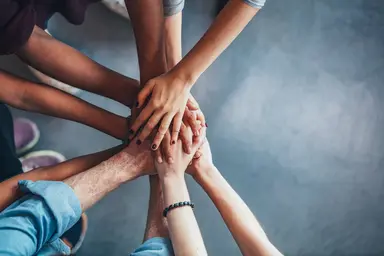People placing their hands together to represent teamwork, collaboration and mutual commitment.