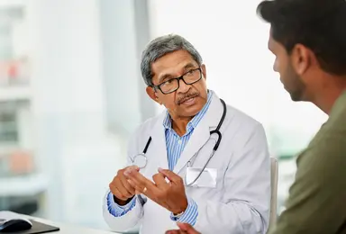 Scientist consulting with a colleague in a laboratory setting, representing expert guidance for diagnostic assay development, vaccine research and infectious disease programmes.