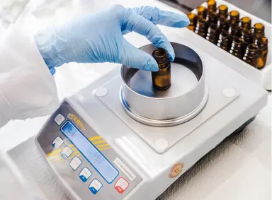 Amber sample vial being weighed on a laboratory balance.