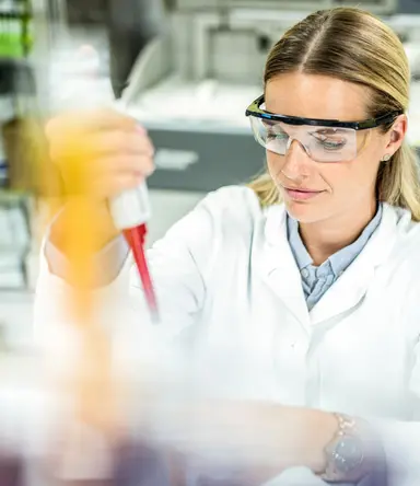 Scientist performing liquid handling with a laboratory pipette during molecular biology sample preparation in a genomics research laboratory.