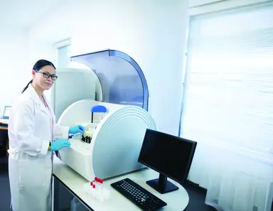 Laboratory professional operating an automated diagnostic analyzer, representing laboratory quality management, accurate testing processes and the role of diagnostics in supporting reliable patient results