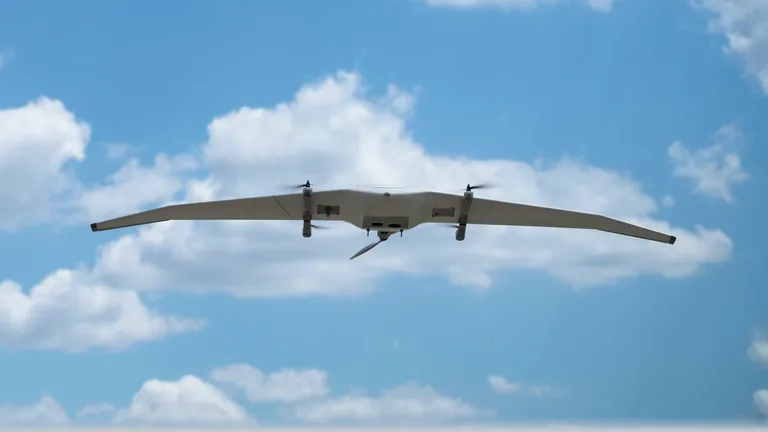 DeltaQuad Evo long range drone flying overhead with a blue sky