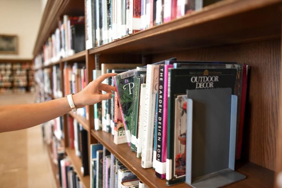 Arm reaching for a book on a full bookshelf