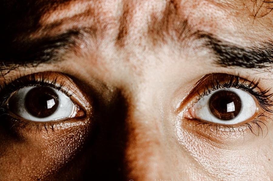 Close-up of a perspiring person's terrified eyes.