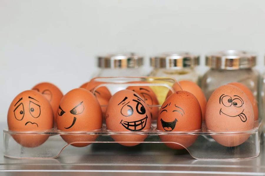 A carton of eggs with different emotional faces drawn on them.