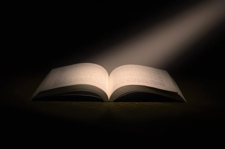 A light shines on the pages of an open book.