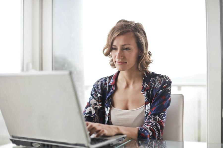 A writer sits at a desk in front of a laptop.