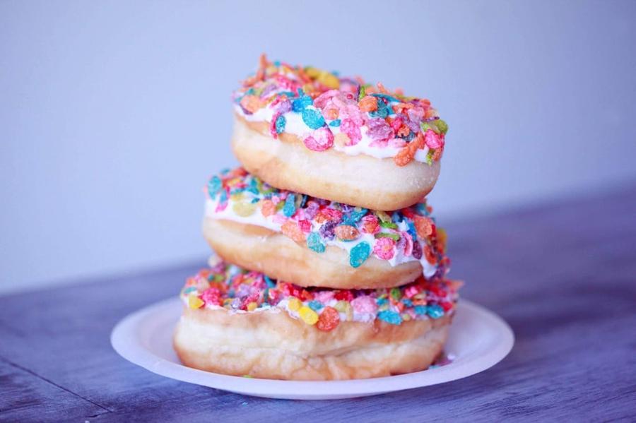 Three sprinkle doughnuts stacked on top of each other.