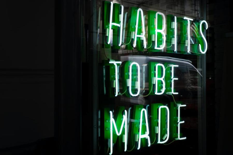 Green neon sign saying "habits to be made"