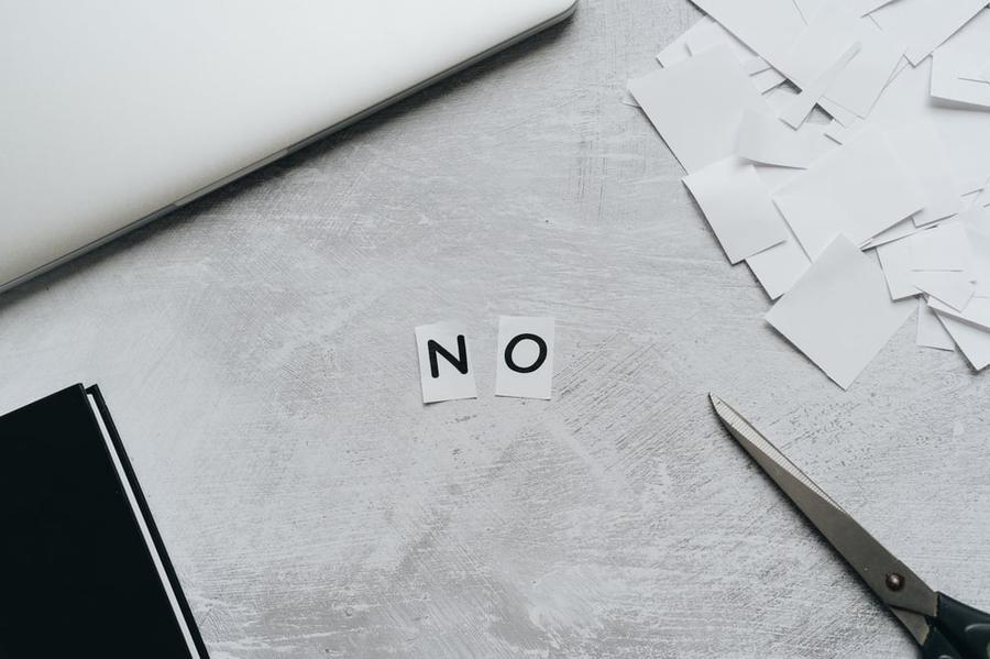 The letters "N" and "O" cut out of paper and placed side by side on a gray desk.