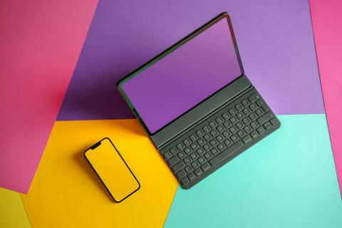 A laptop and a phone on a bright, multicolored background.