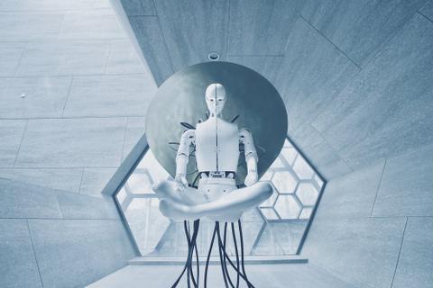 A white robot sits with legs crossed on a futuristic chair.