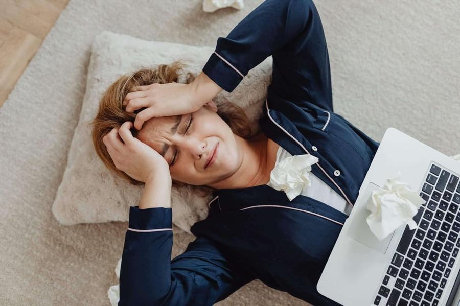 Woman experiencing writer's block, holding her forehead and laying on a pillow