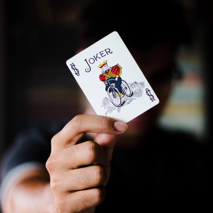 Close-up of a hand holding a Joker playing card.