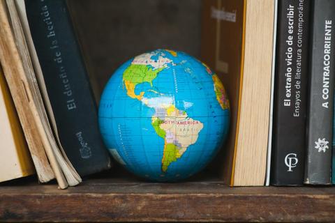 A globe sits between books on a bookshelf.