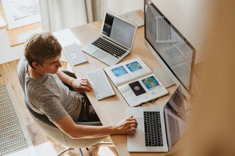 A writer sits in front of three different computer screens.