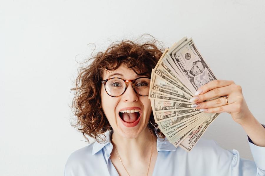 An excited woman holding up a bunch of cash