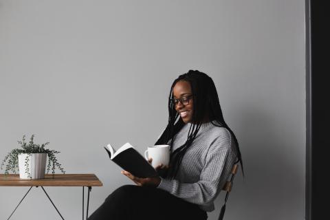 Woman sitting at a table reading a book.