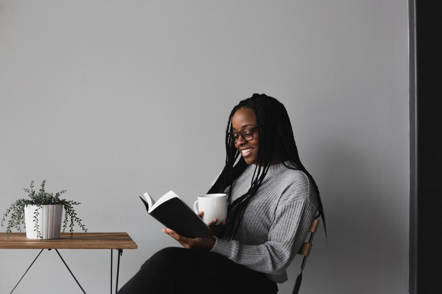 Woman sitting at a table reading a book.